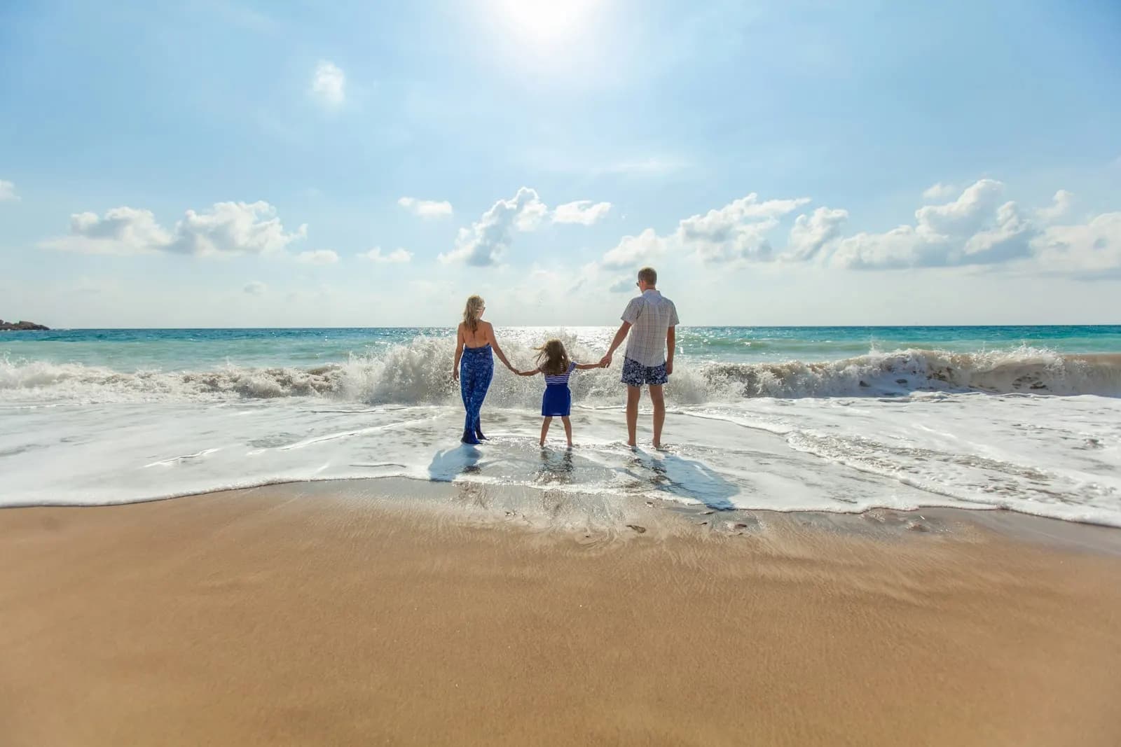 An adult and child holding hands on an Aruba seashore