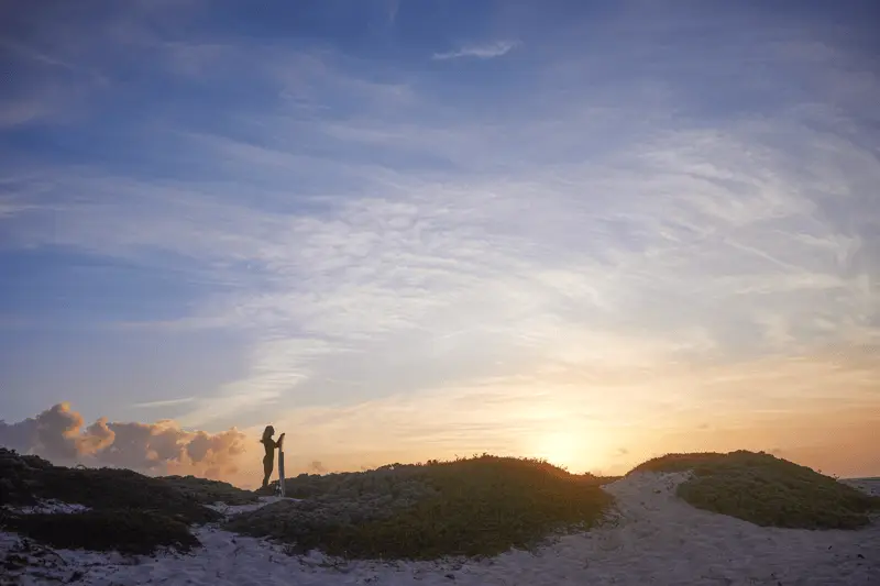 A woman relaxing in a beach lounge chair at sunset in Aruba
