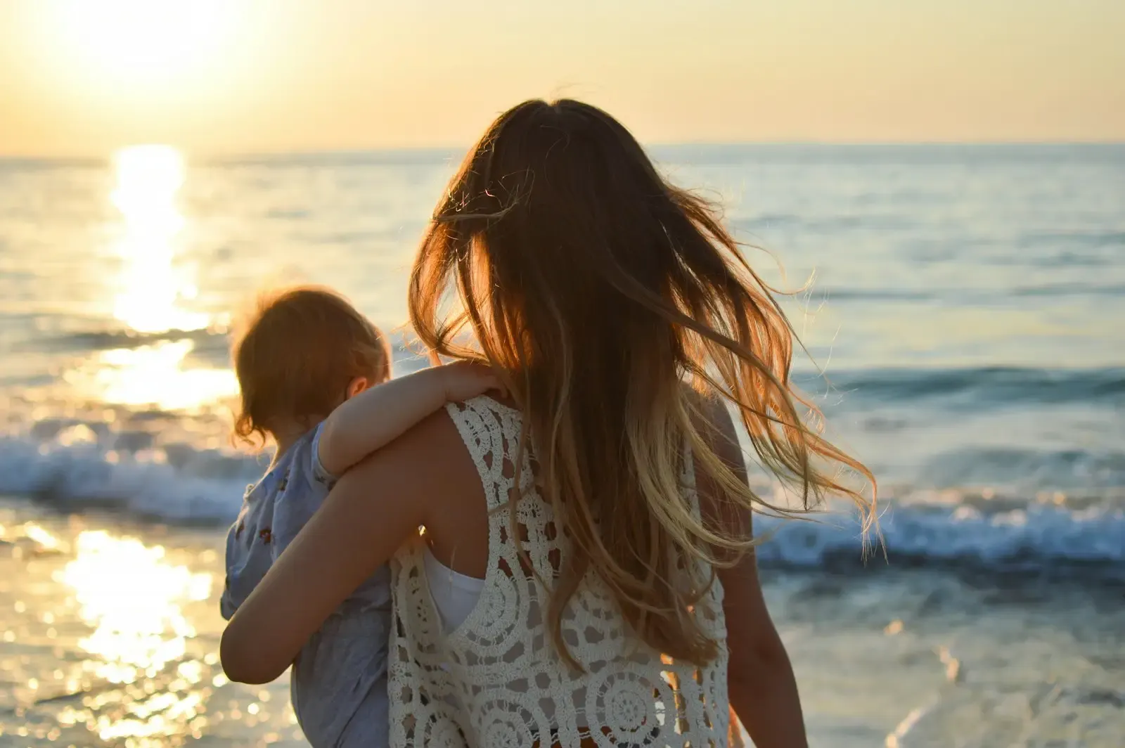 A parent carrying a child beachside in Aruba