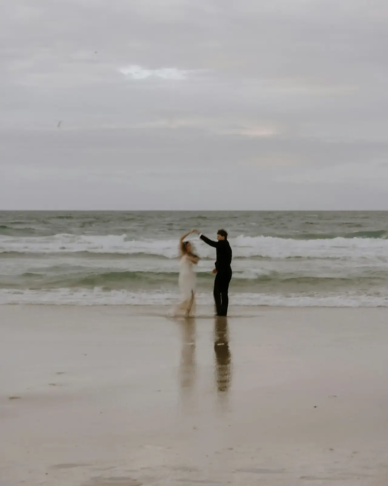 A couple in wedding attire running through the shallows on an Aruba beach