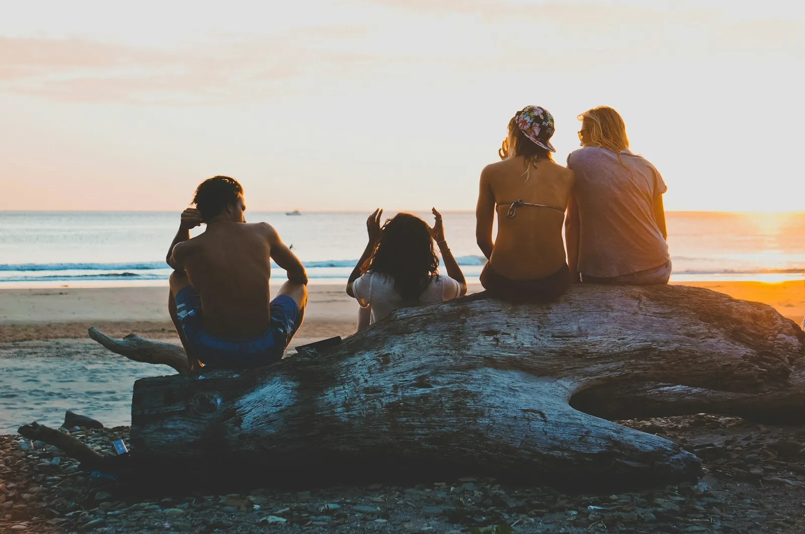 Three women sitting on a rock on an Aruba beach