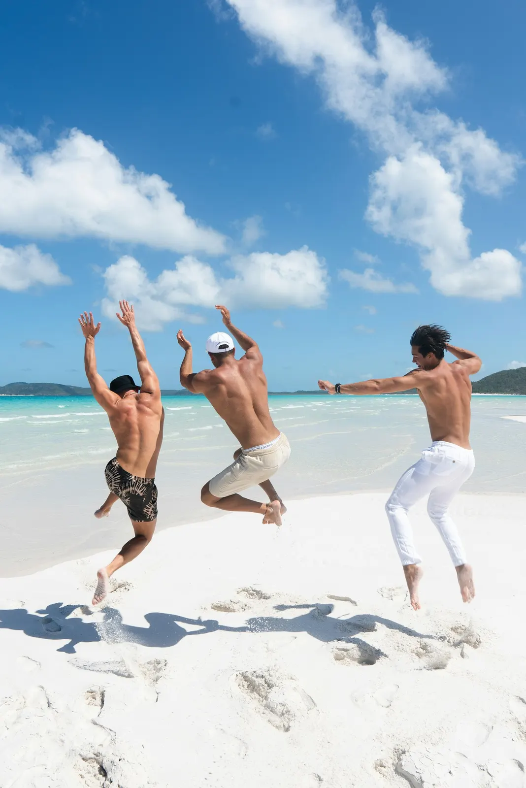 Two women running together on a white sand beach