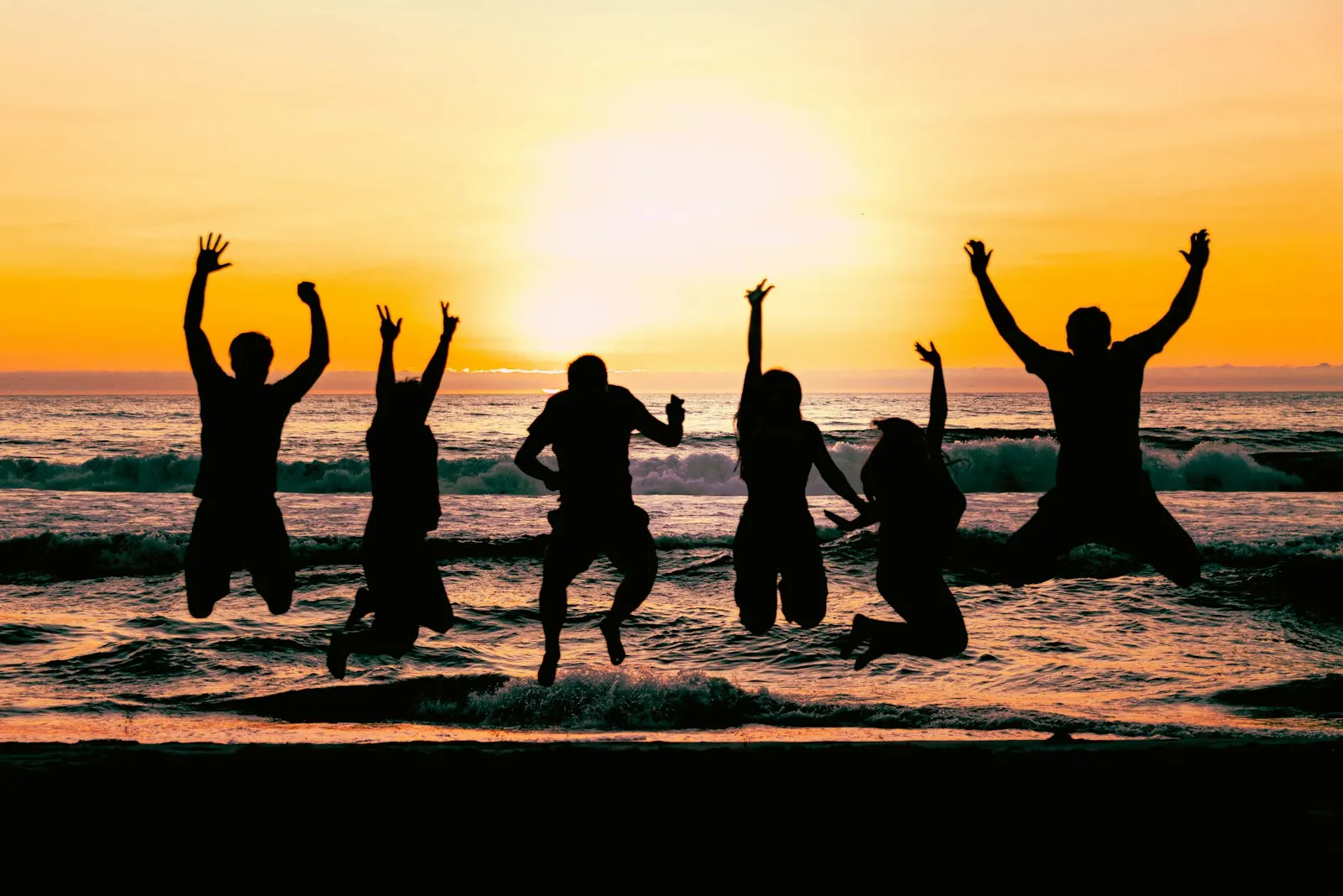 A group of friends jumping together on the beach