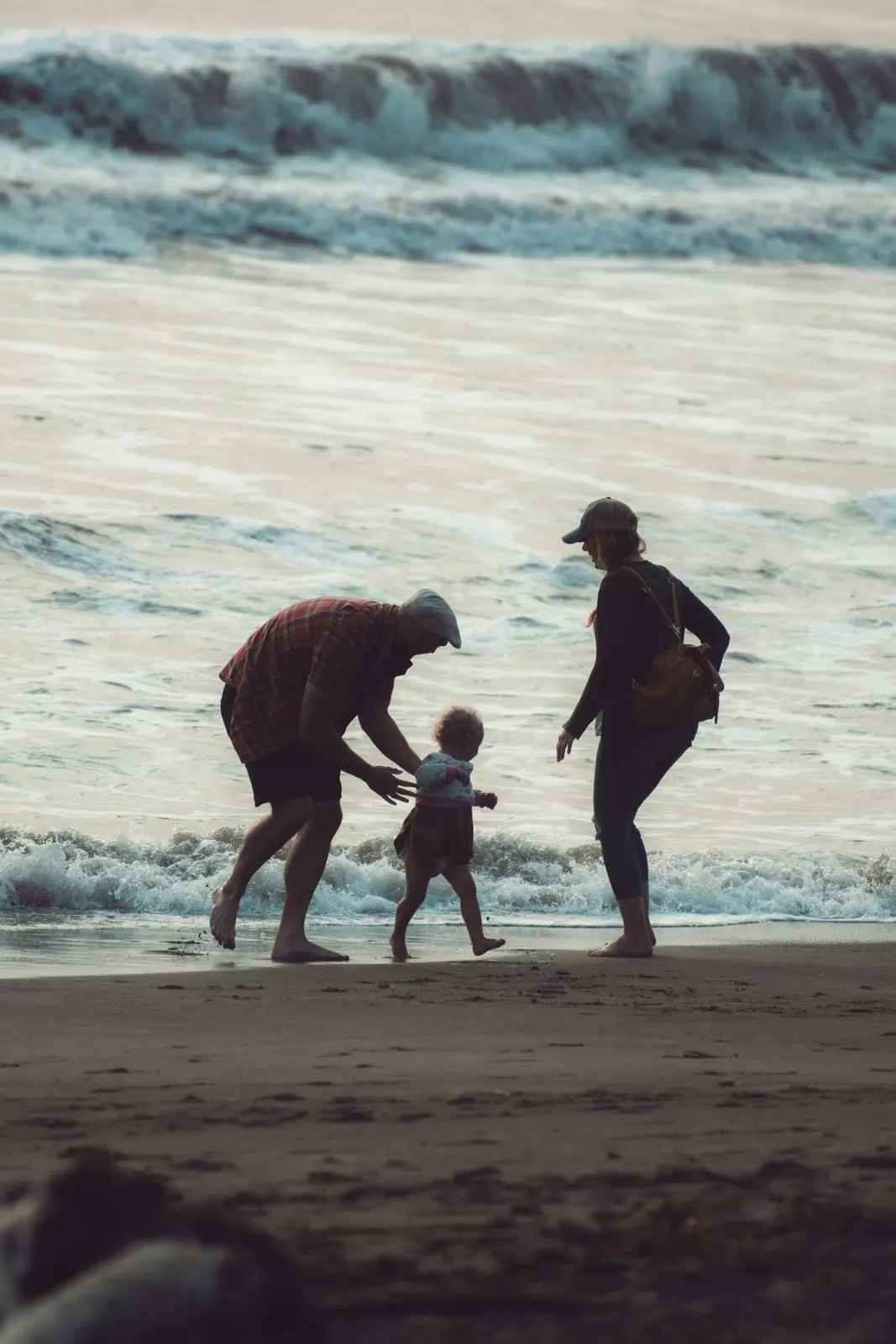 An adult carrying a child on an Aruba beach