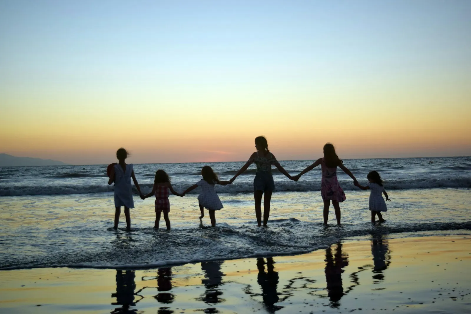 A family holding hands together on an Aruba beach at sunset