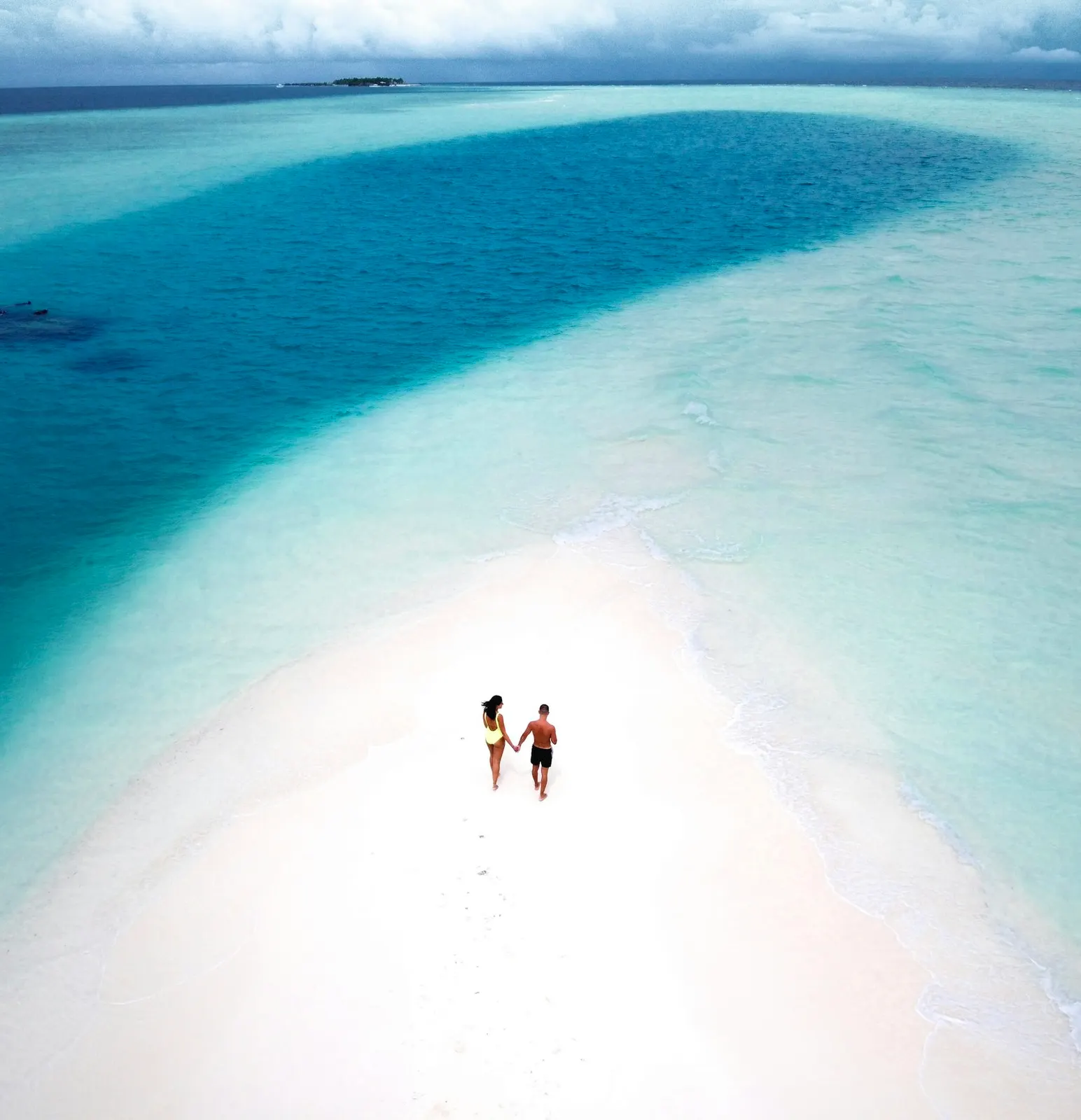 Two people walking together on a sandbar in Aruba