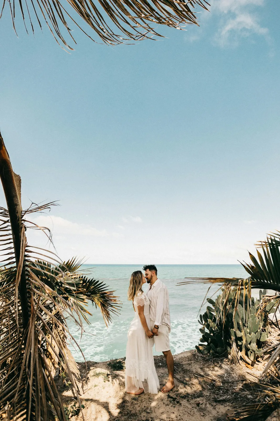 A couple standing together near a palm tree on an Aruba beach
