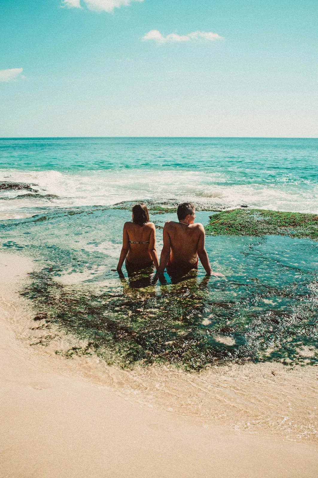 A woman and man wading together on an Aruba beach