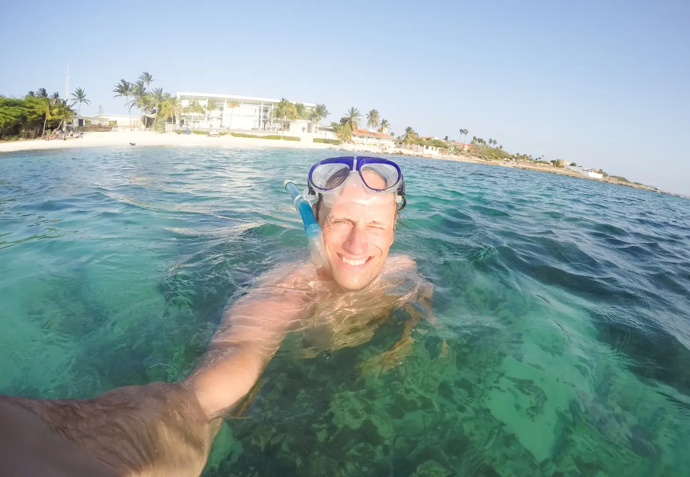 A snorkeler smiling at the camera in the clear turquoise water off Aruba's coast